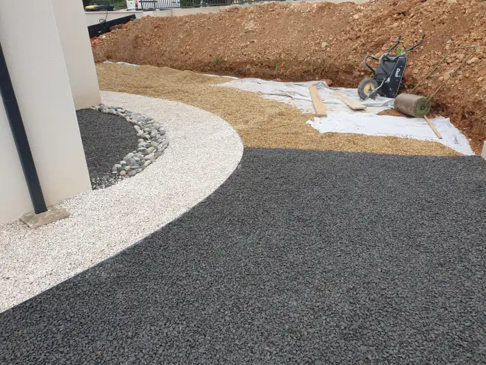 Gravier blanc, gravier noir et galets formant des courbes au pied d’une maison